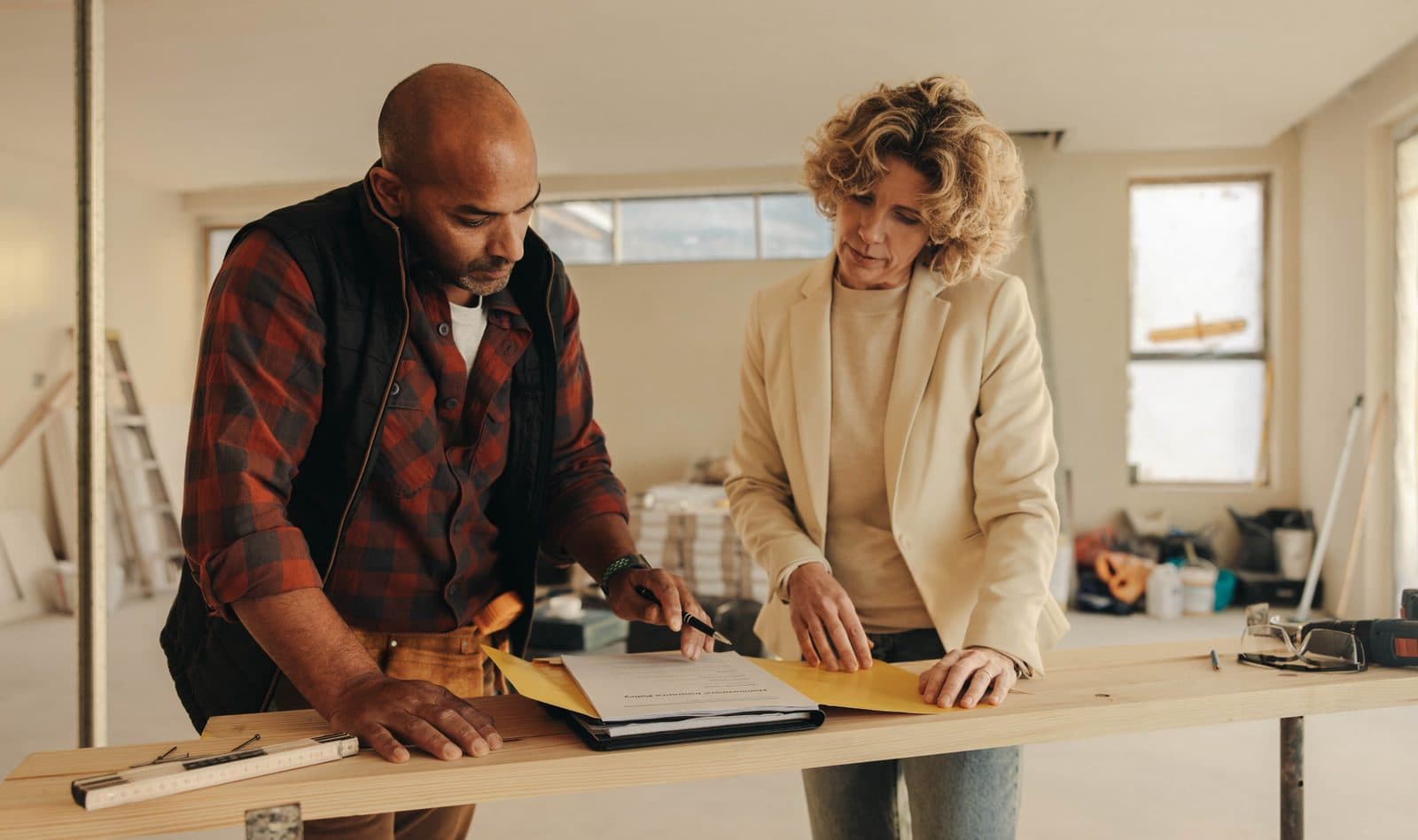 A tradie and homeowner reviewing paperwork together on-site