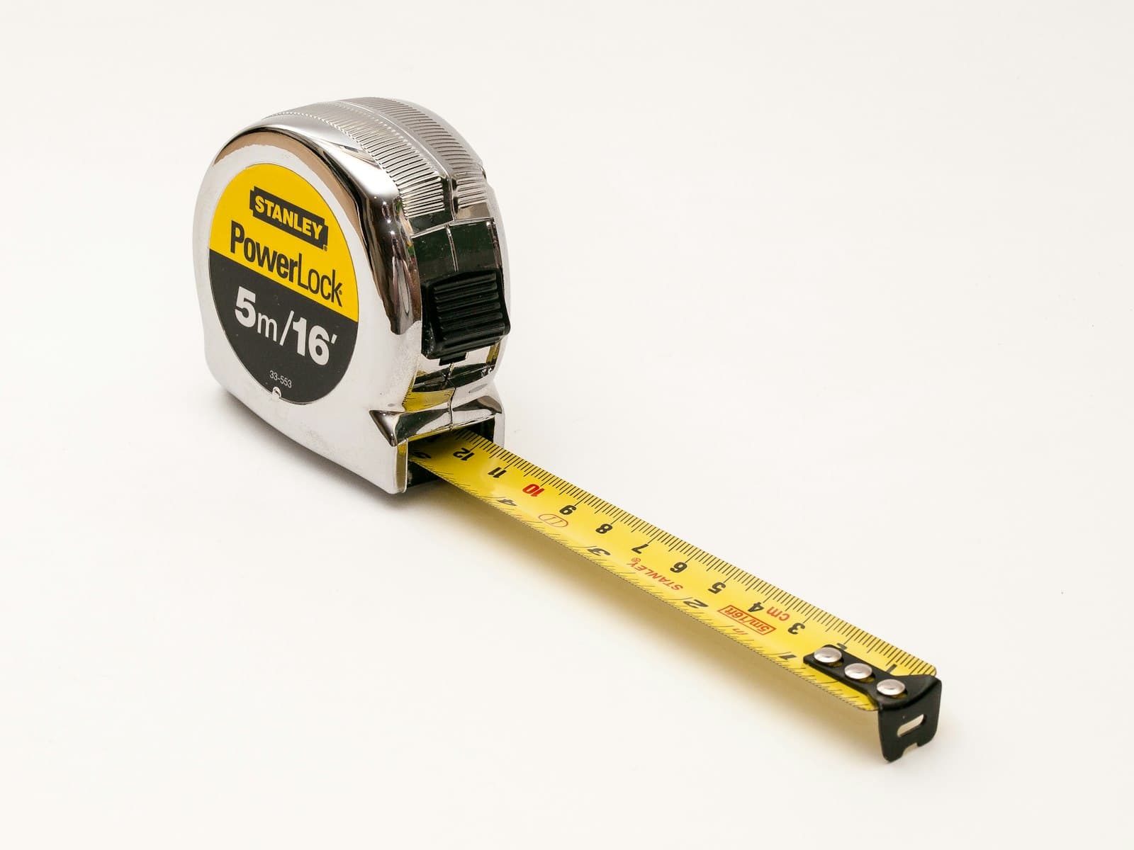 A metal tape measure extended on a white surface