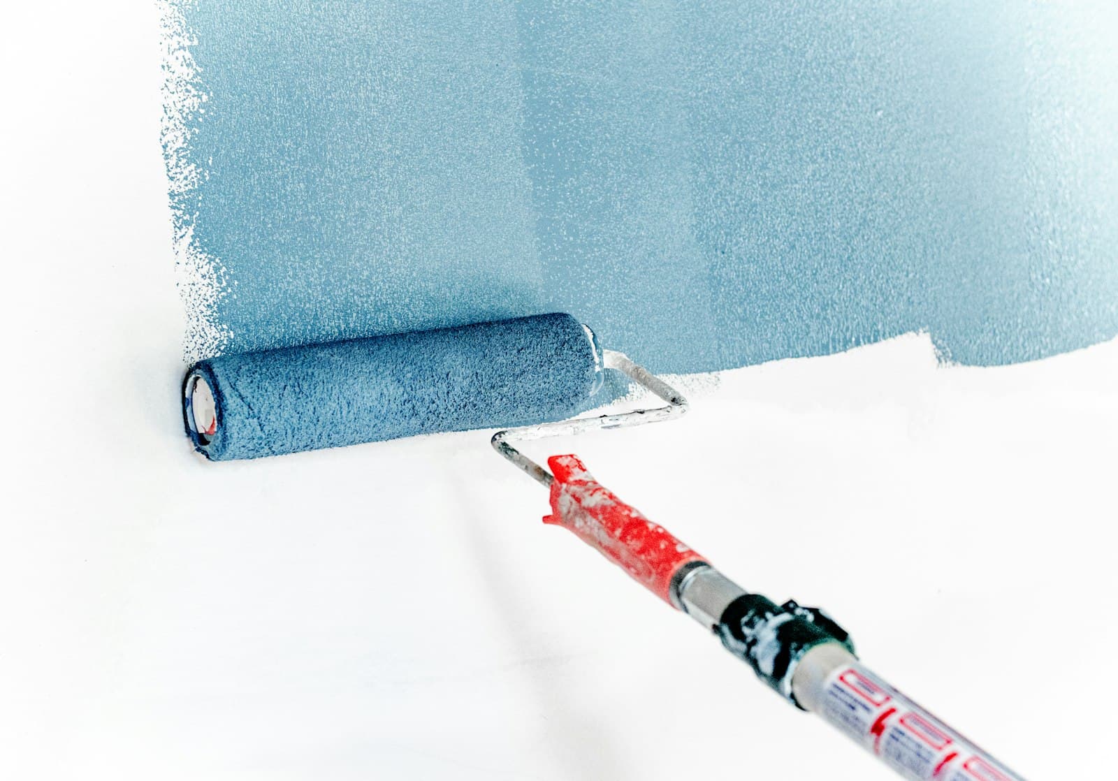 A paint roller applying fresh paint to a wall