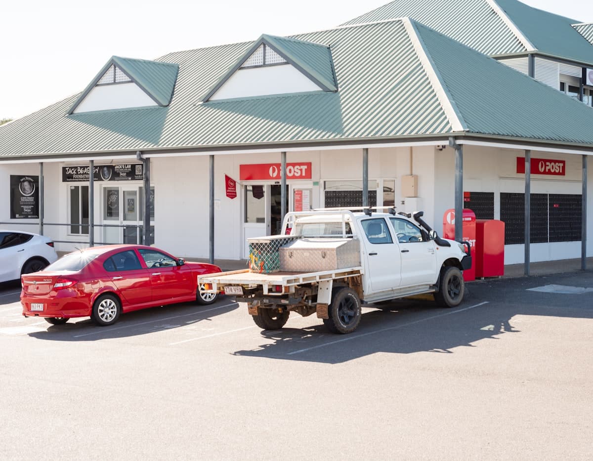 A white tray-back ute parked outside a country town shop